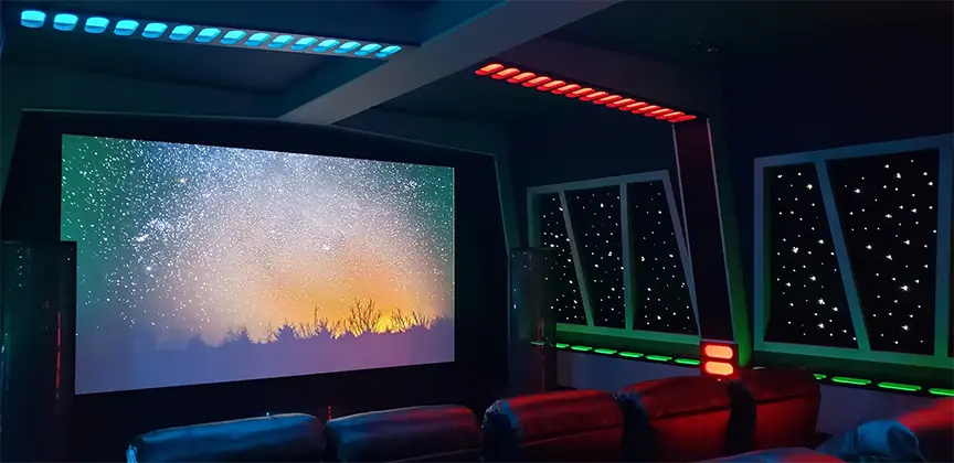 Star Wars dark home movie theater seating scene with star panels on the walls and red and blue led perimeter lighting across the ceiling to make it look like a space ship.